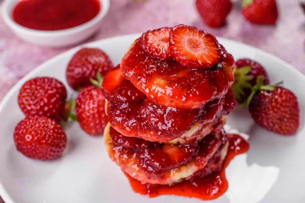 Cottage Cheese Pancakes With Sliced Strawberries And Strawberry Jam On A Plate On A Concrete Background