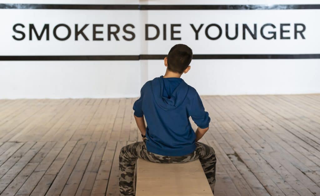 Teenager Smoking And Message On Wall Smokers Die Younger. No S
