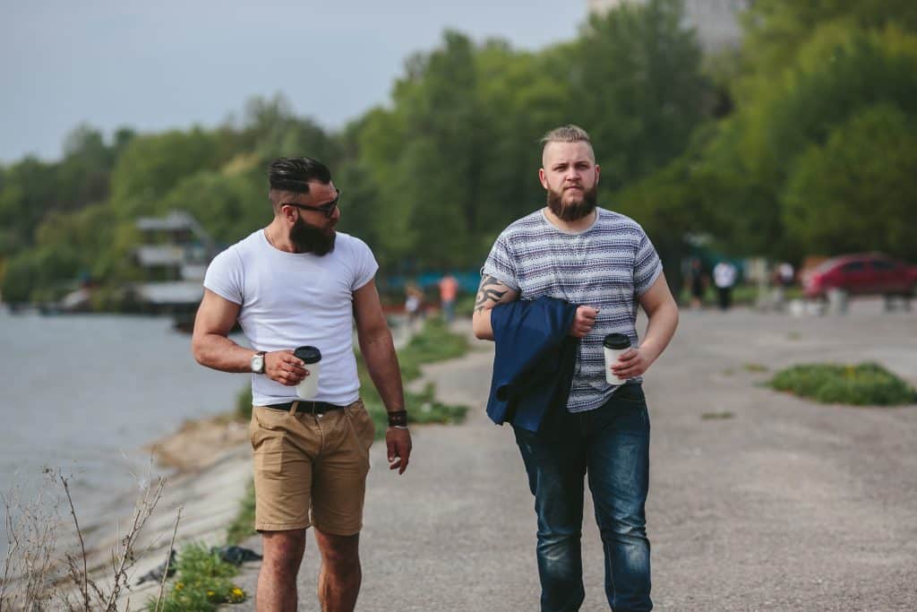 Two Men Walk And Drink Coffee