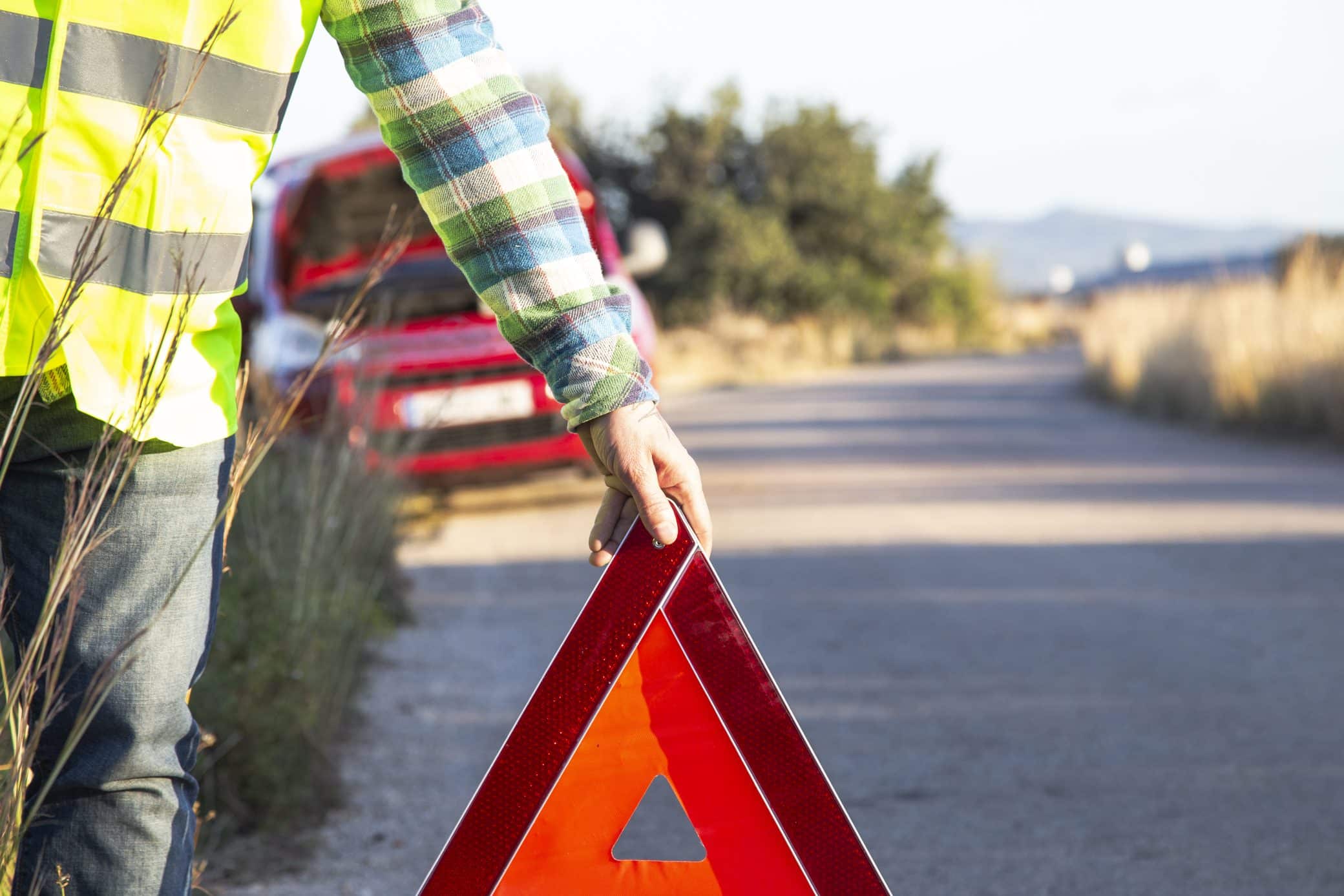 A Man Putting A Warning Triangle Behind His Car