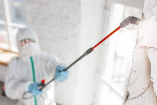 Coronavirus Pandemic. A Disinfector In A Protective Suit And Mask Sprays Disinfectants In The Room.