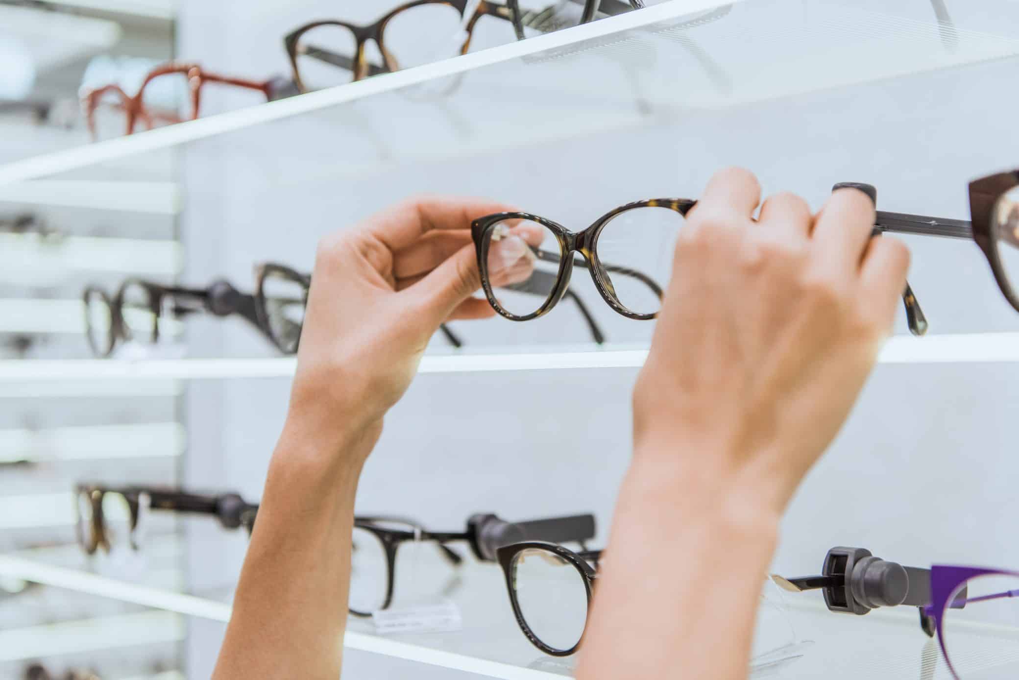 Partial View Of Optician Taking Glasses From Shelf In Ophthalmic Shop