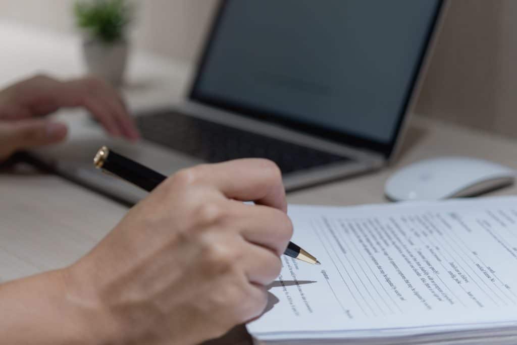 Hand Using Writing Pen With Paperwork In Business Company Personal Information Or Signature Job Application Documents On Desk.