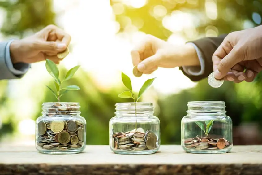 Businessman Hands Putting Money (coin) Into The Glass Jar