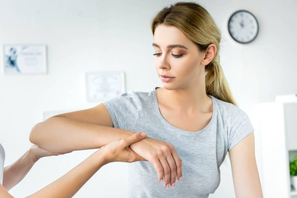Chiropractor Touching Hand Of Attractive Patient In Grey T Shirt