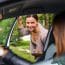 Une femme souriante regarde à l'intérieur d'une voiture à travers la fenêtre ouverte.