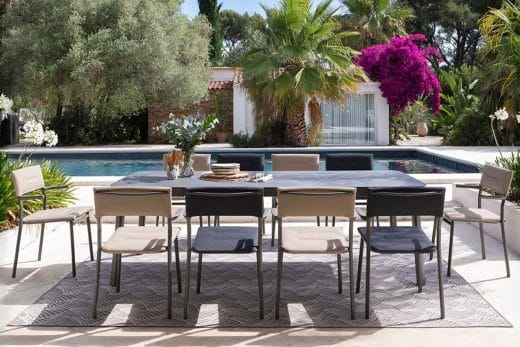 Salon de jardin moderne avec table et chaises près d'une piscine.