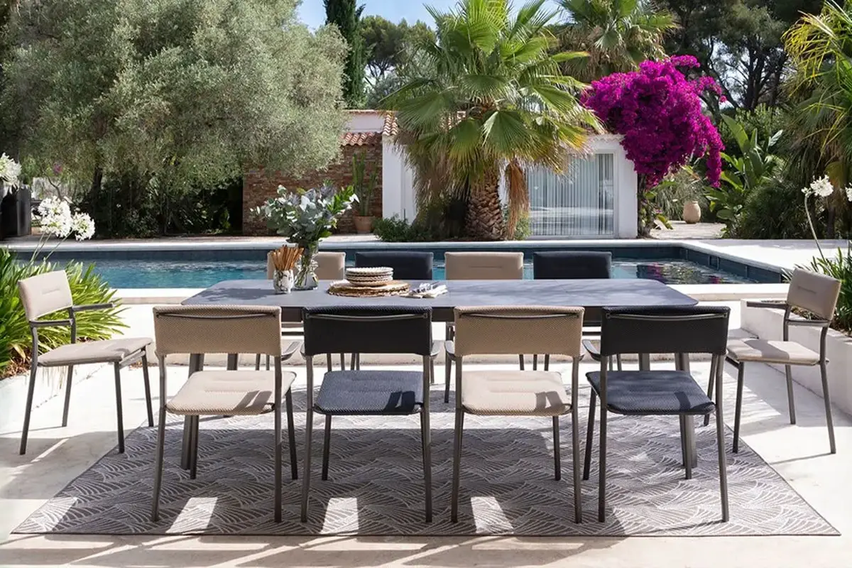 Salon de jardin moderne avec table et chaises près d'une piscine.