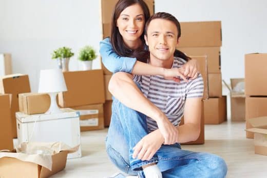 Couple assis devant des cartons de déménagement.