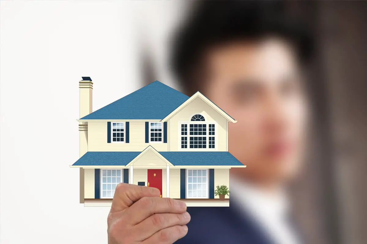 Agent immobilier tenant une petite maison en modèle.