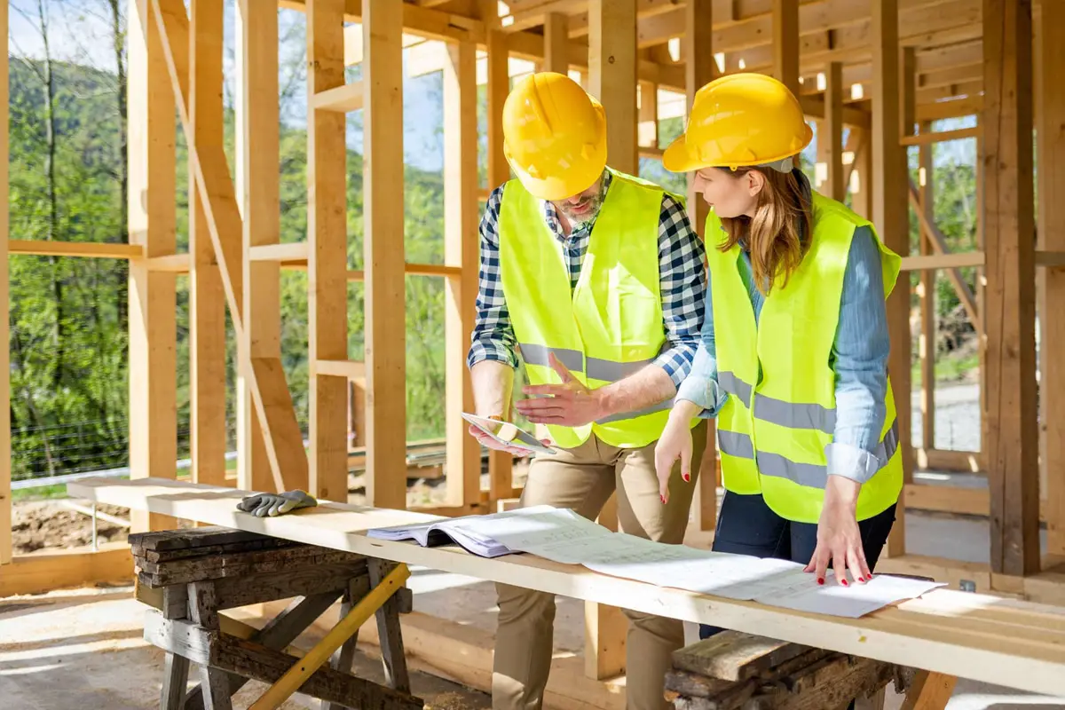 Deux entrepreneurs discutent des plans dans une maison en construction.