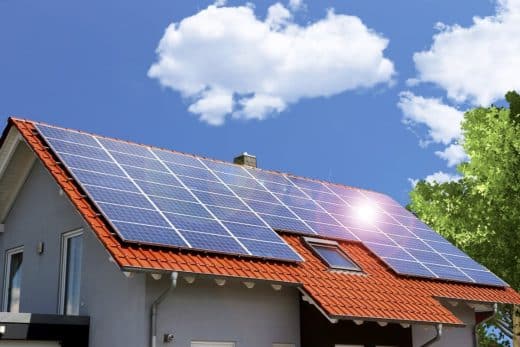 Maison avec panneaux solaires sur le toit sous un ciel bleu.