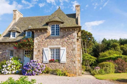Vieille maison en pierre avec des fleurs dans le jardin.