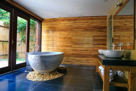Salle de bains moderne avec baignoire en pierre et murs en bois.