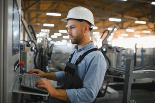 Operator Wearing Safety Hat Behind Control Panel On A Factory