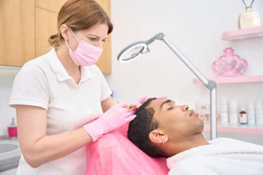Professional Trichologist Treating Young Man For Hair Loss