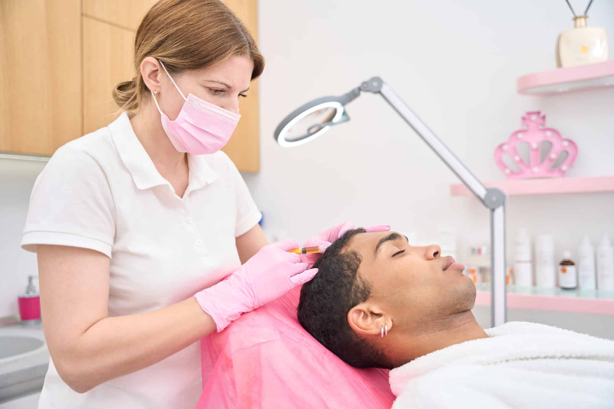 Professional Trichologist Treating Young Man For Hair Loss