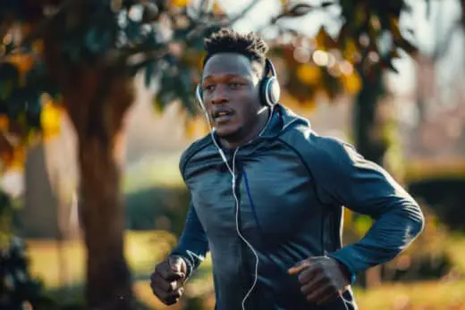 A Dedicated Sportsman Of African Descent Finds His Rhythm While Running Outdoors, His Headphones Piping Motivating Music Into His Ears.