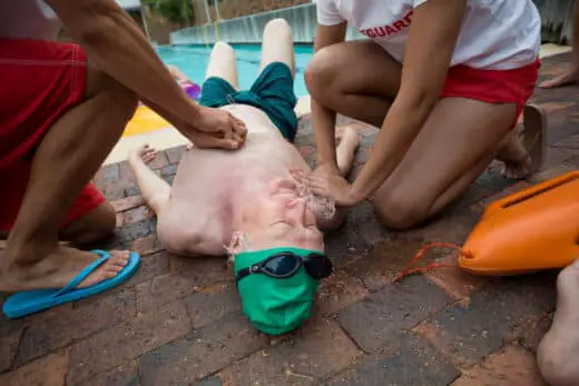 Lifeguards Helping Senior Man At Poolside