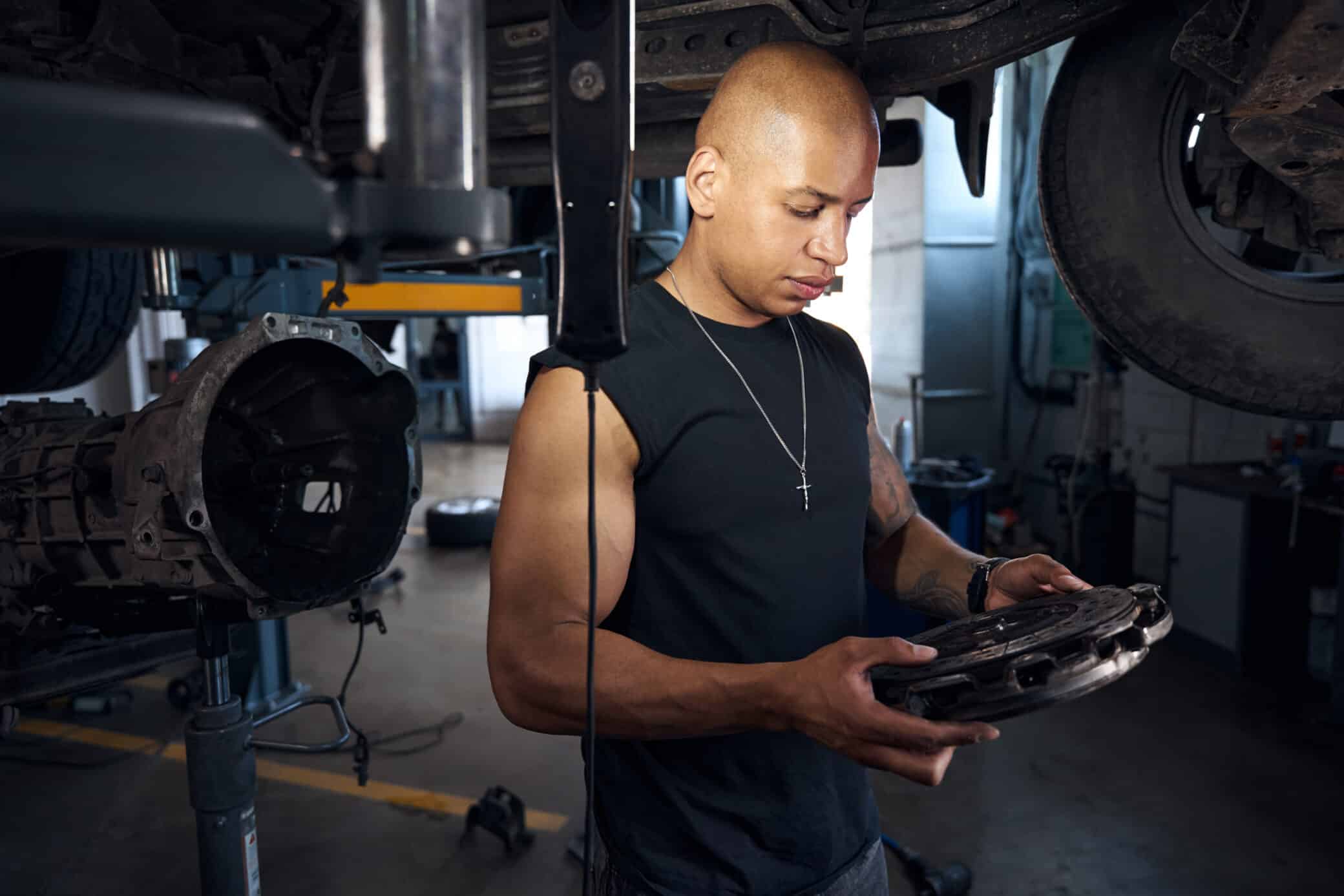 Auto Mechanic Looking At Clutch Disc Searching For Problems