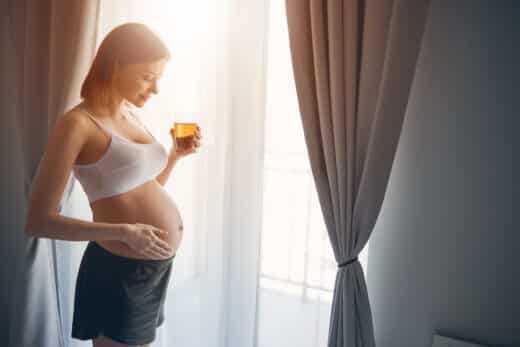 Young Future Mother Standing Near The Window At Home